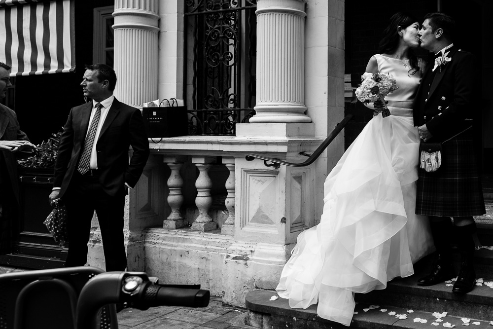 black and white image of bride and groom kissing on Mayfair library steps