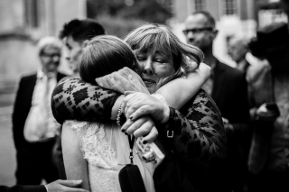 black and white shot of guest hugging the bride on the way to one whitehall place London