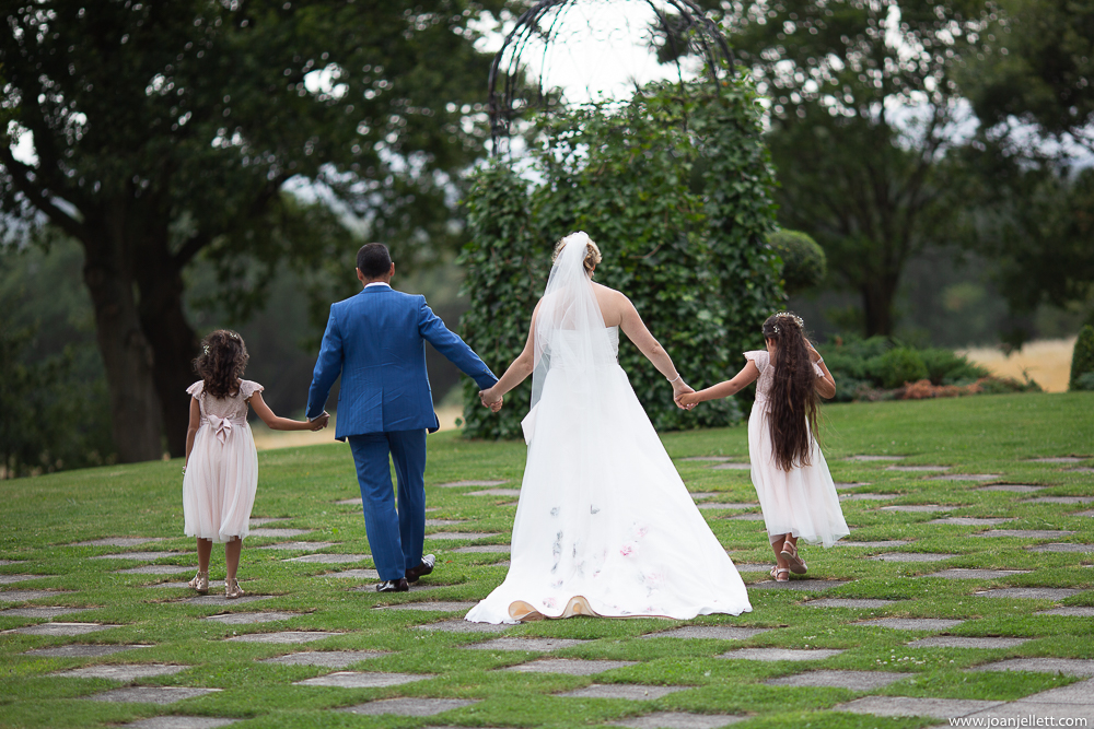 bride and groom holding hands with their daughters