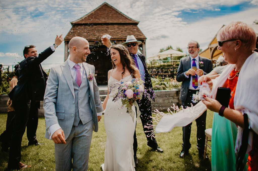 confetti shot of bride and groom looking at each other whilst walking