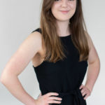 Commercial photographer Bournemouth with her hands on her waist smiling wearing a black dress