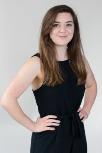 Commercial photographer Bournemouth with her hands on her waist smiling wearing a black dress