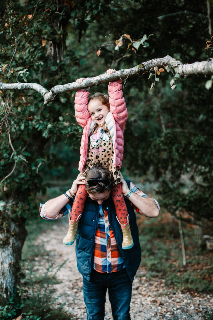 little girl hanging off a branch laughing