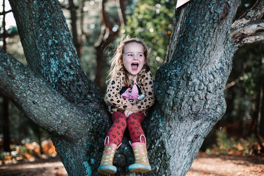 little girl sat on a tree laughing at her mum