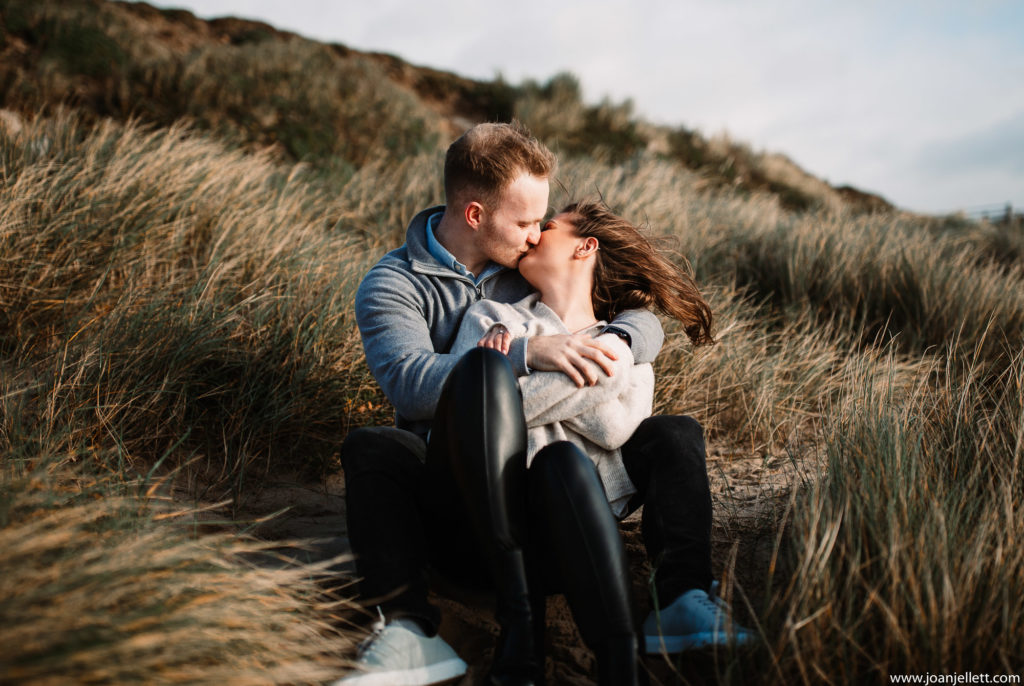 couple kissing on a dune in Engagement photoshoot in hengistbury head