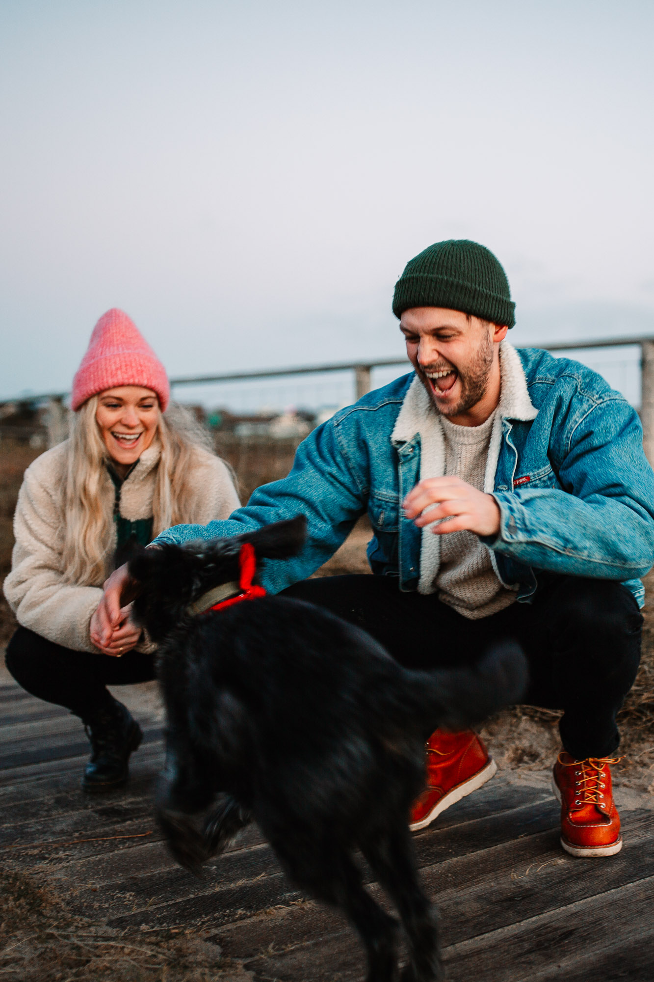 couple playful laughing with their black little dog