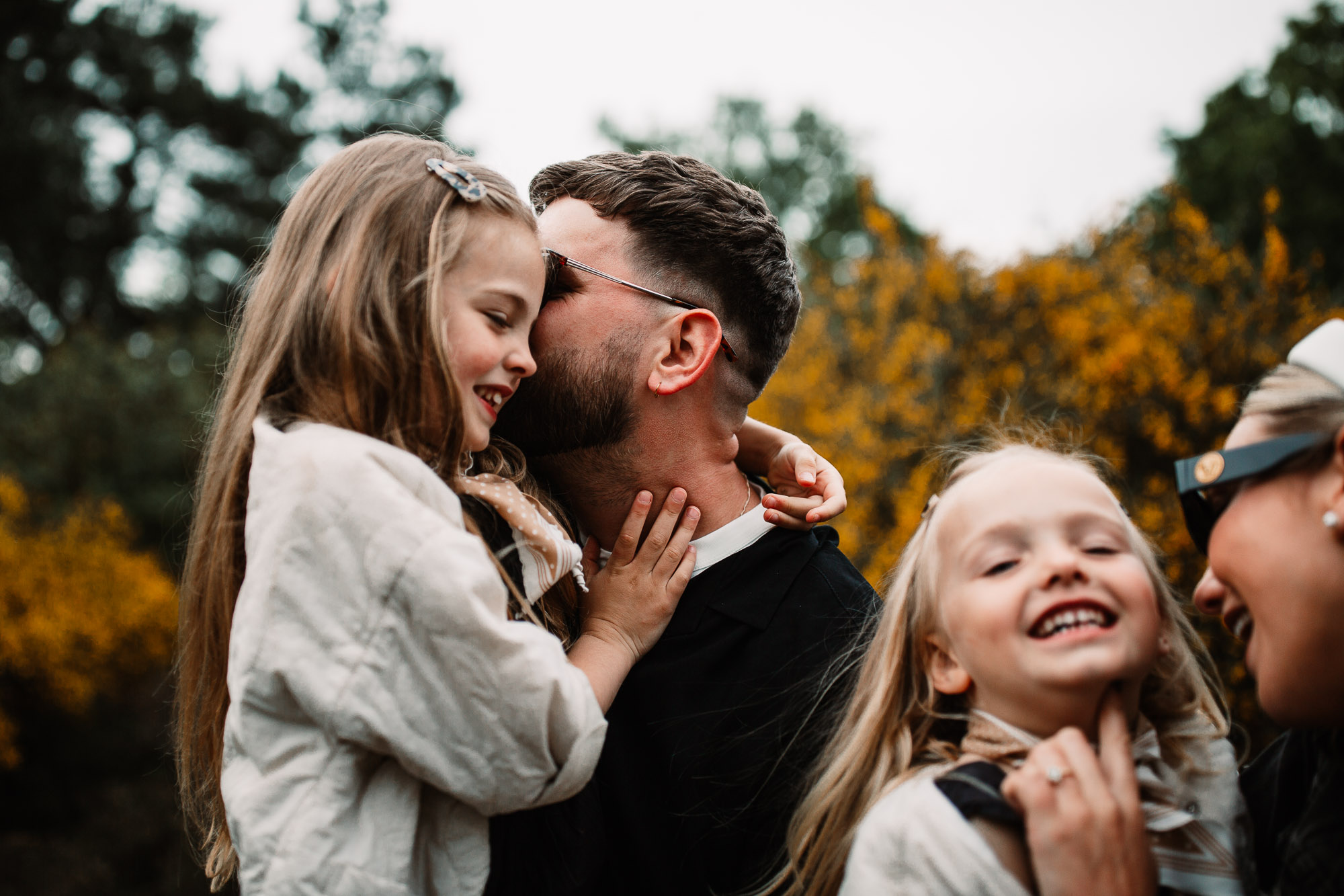 dad kissing daughter in the forest on the cheek