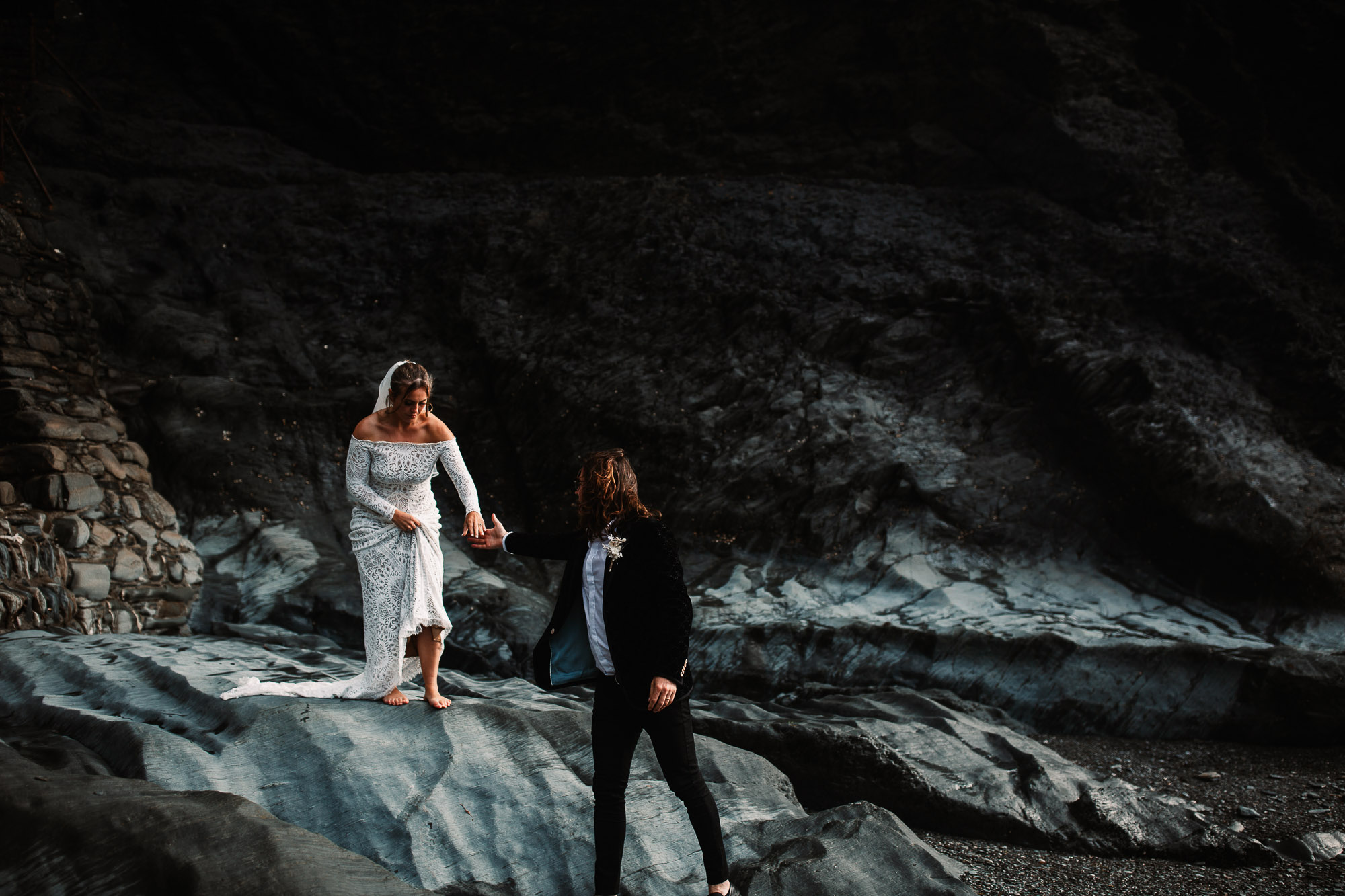 groom helping bride during portraits at tunnels beaches golden hour