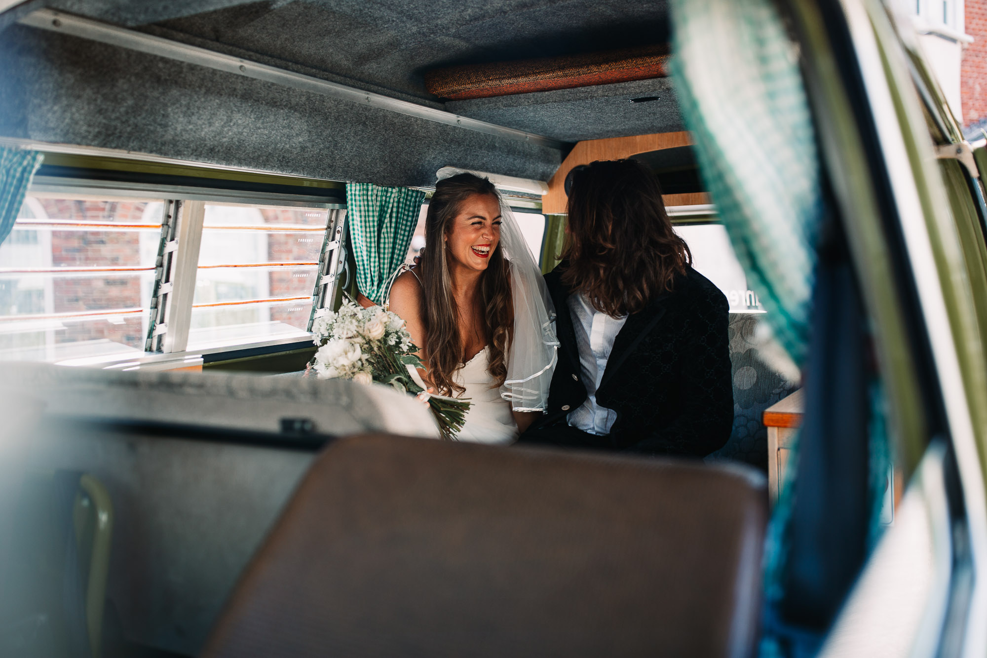bride laughing with her husband inside their car