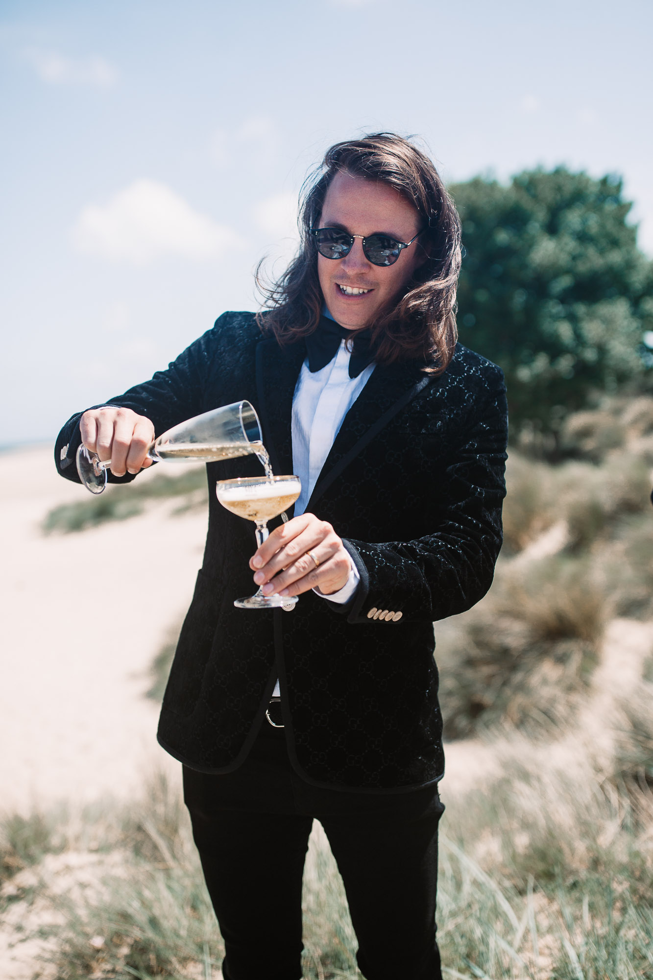 groom pouring champagne on the beach in dorset
