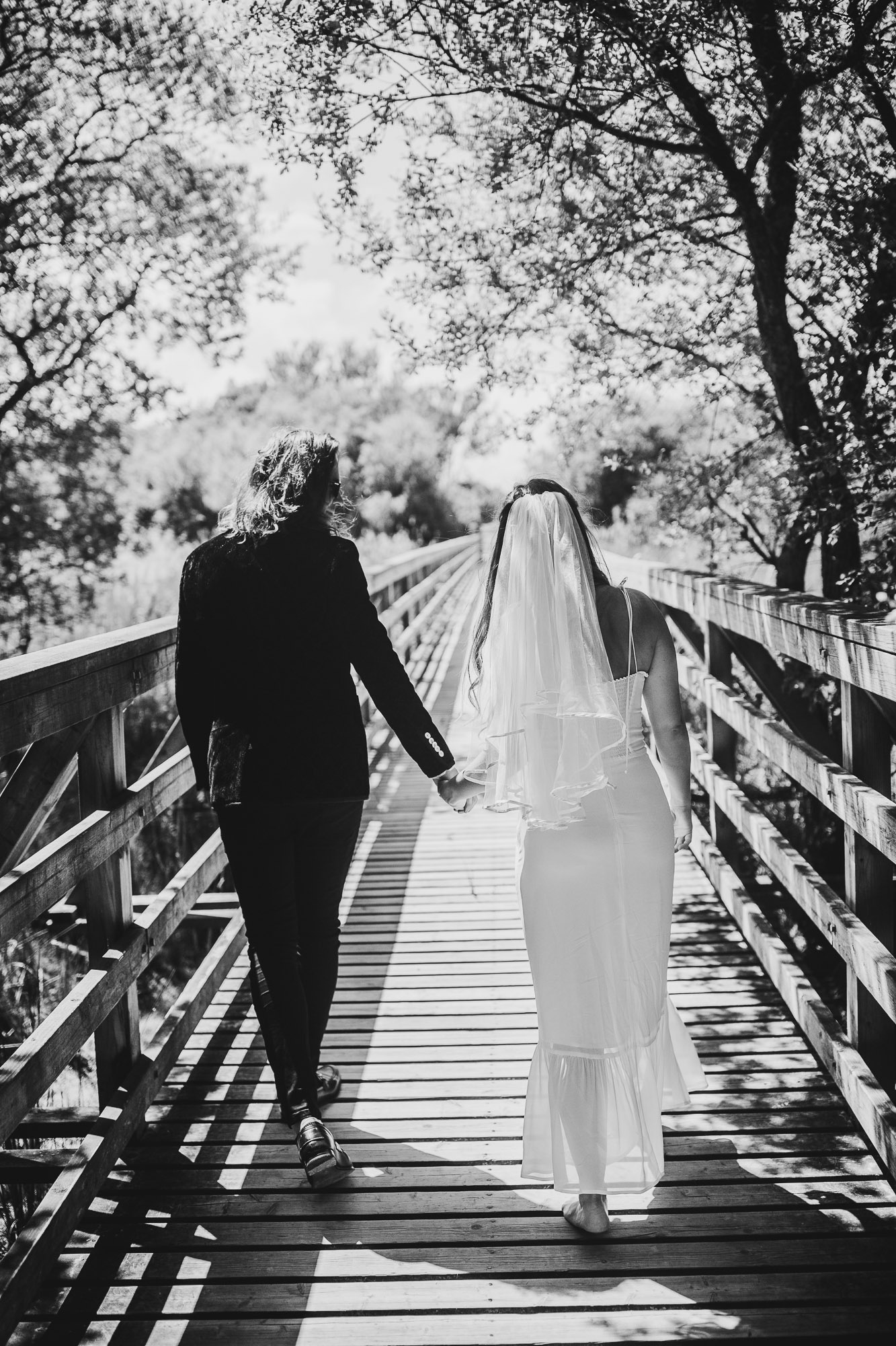 black and white shot of bride and groom walking on shell bay beach