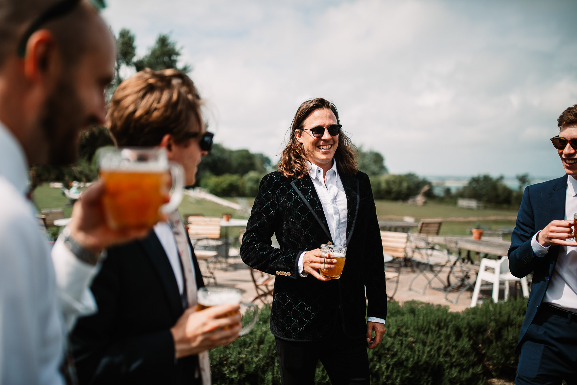 groom holding a beer and laughing with his guests