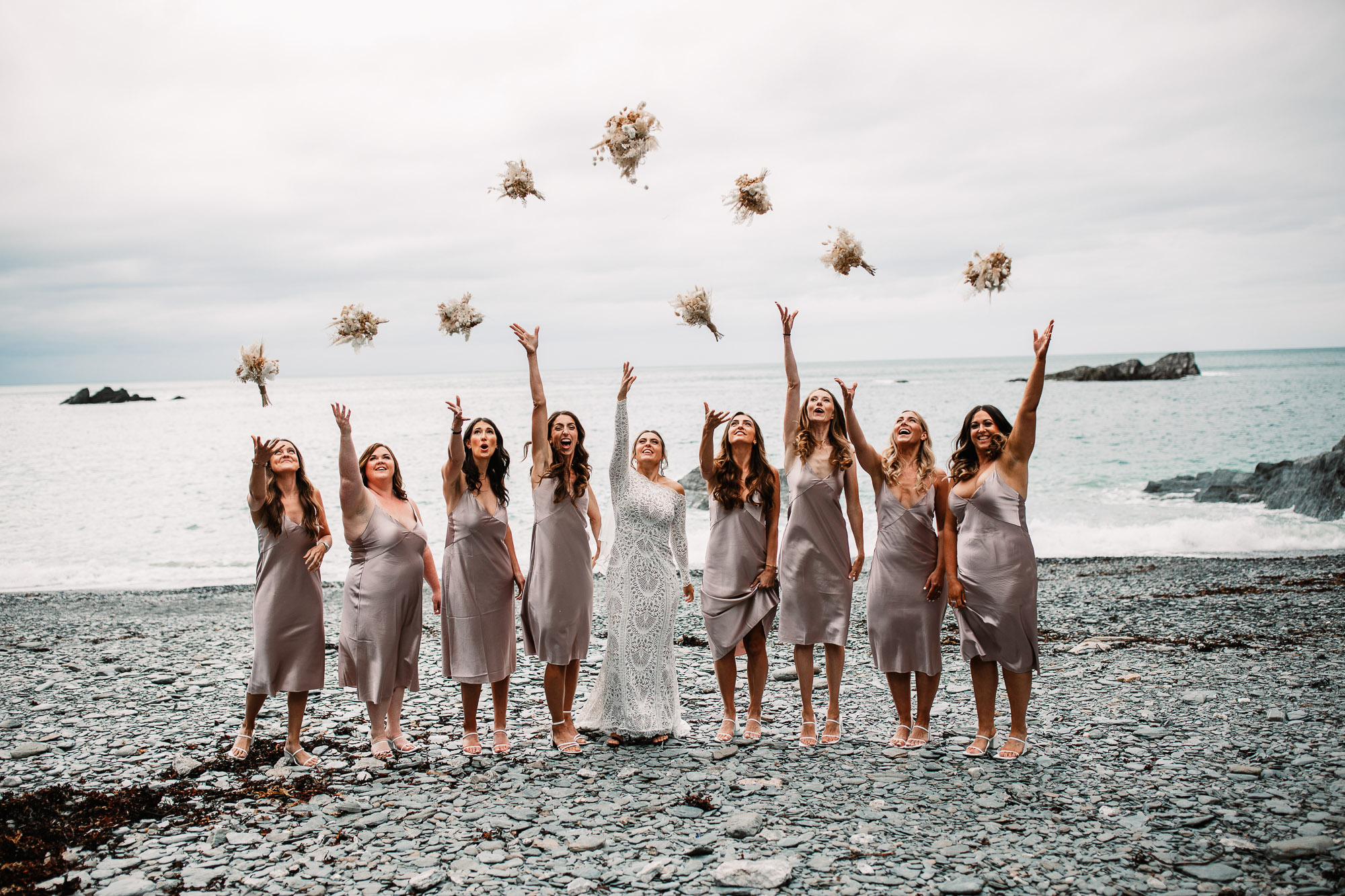 the girls throwing their bouquet in the air on the beach