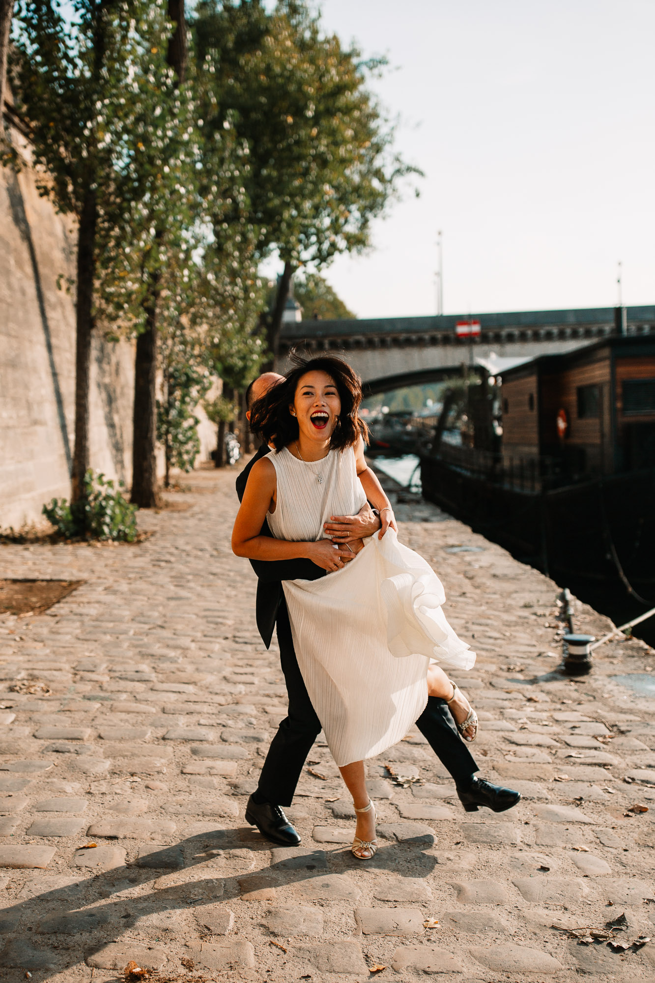 Bride being lifted up by her husband in Paris, laughing looking at the camera