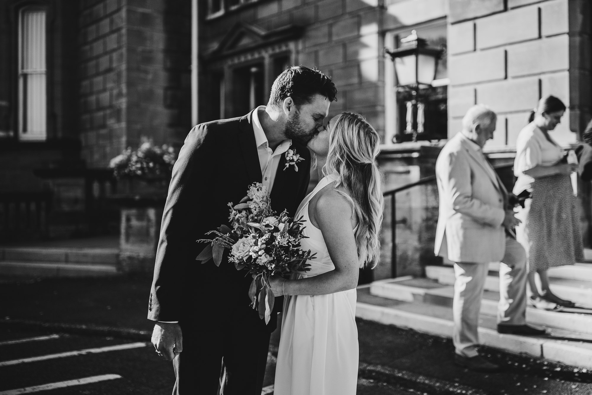 black and white shot of bride and groom kissing outside of bournemouth registry office