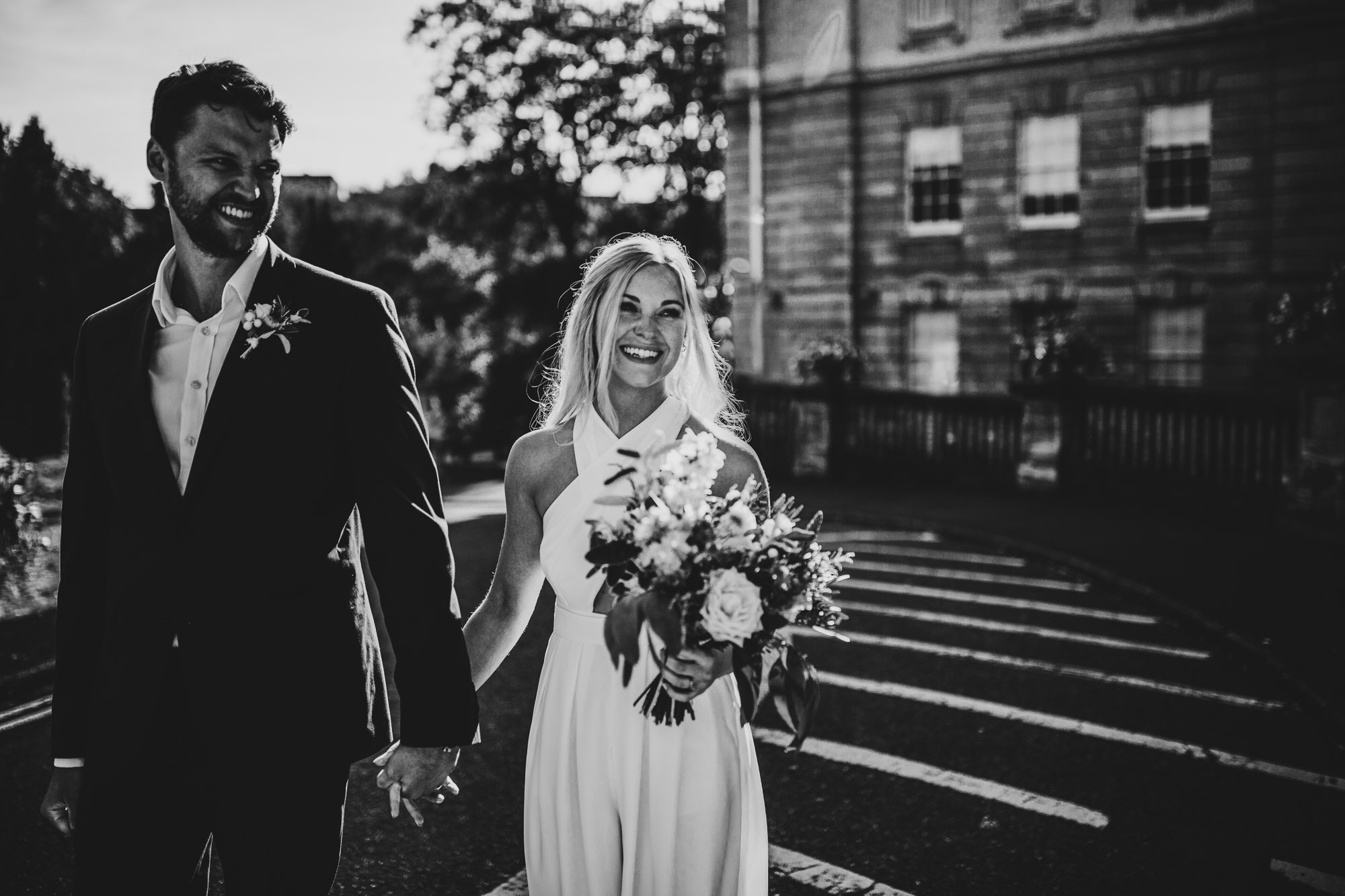 black and white image of groom and bride laughing and smiling outside