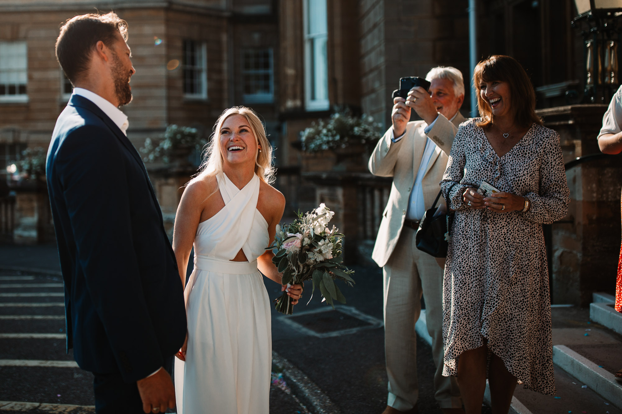 bride laughing with groom whilst having their pictures taken