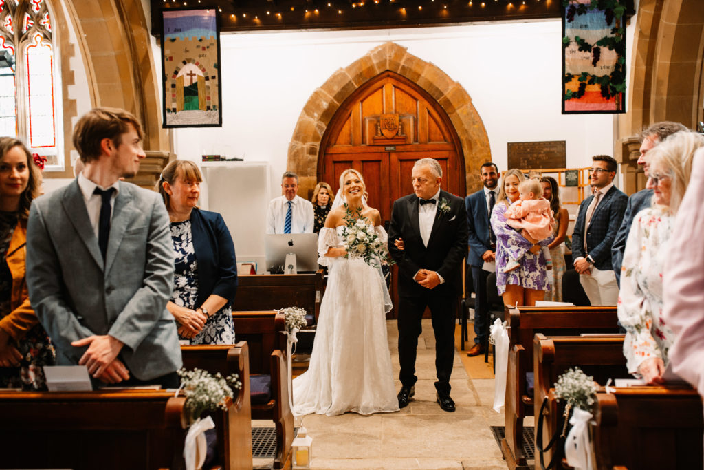 bride seeing her groom whilst holding her dad's arm