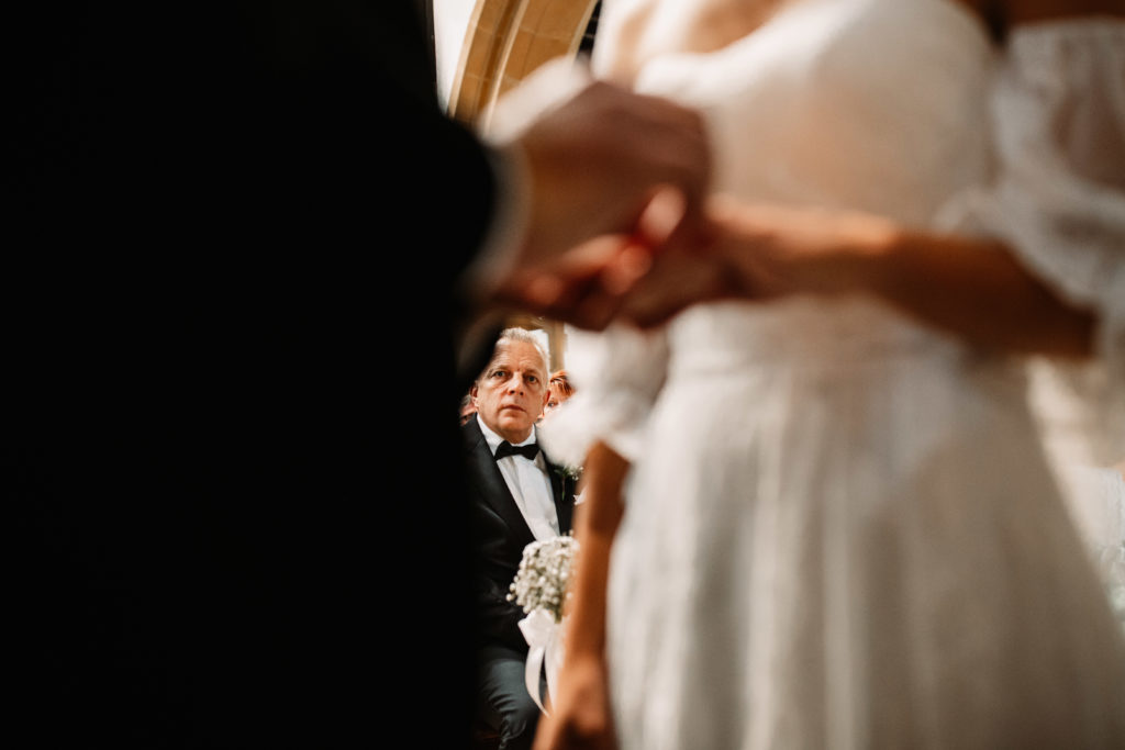 father of the bride looking at his daughter putting ring on her new husband