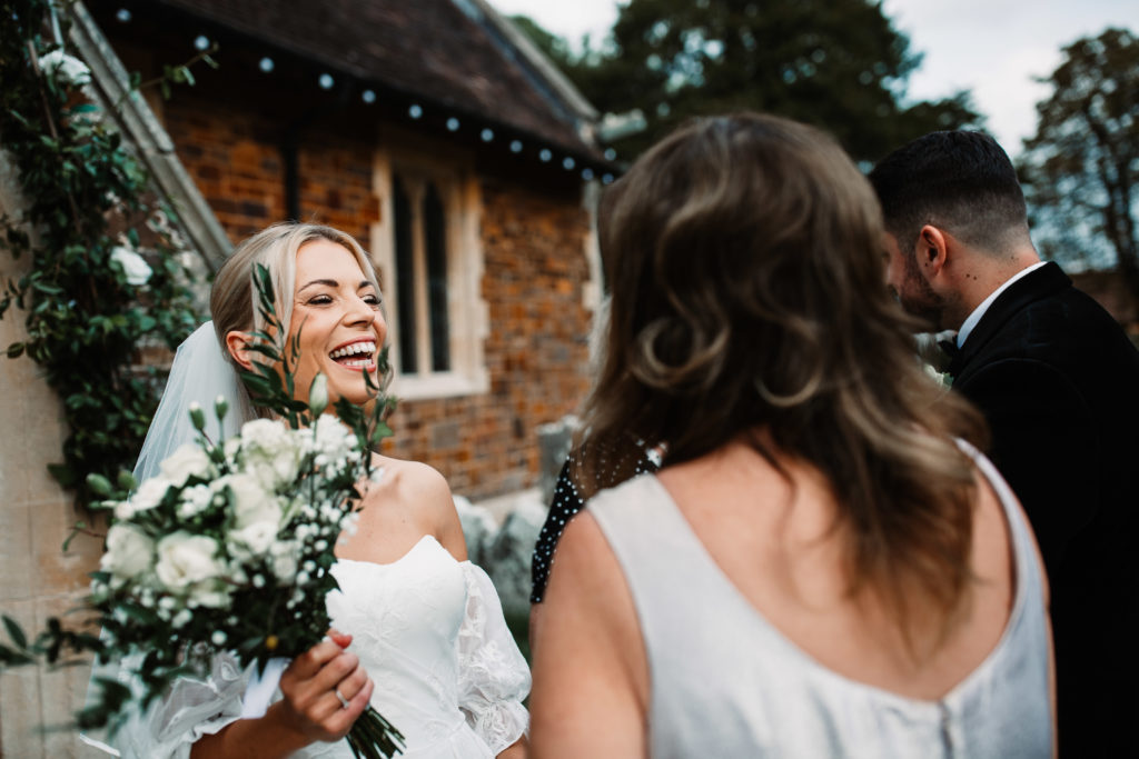 bride holding her bouquet up and laughing with guests