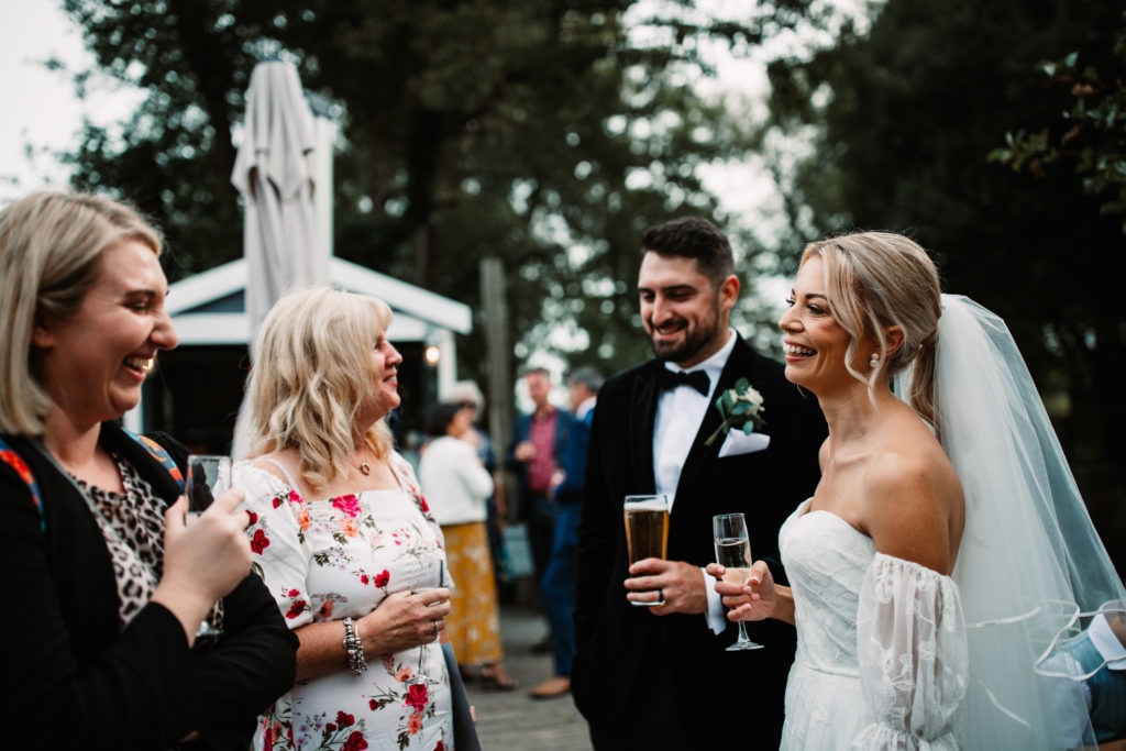 bride drinking champagne and laughing with her guests