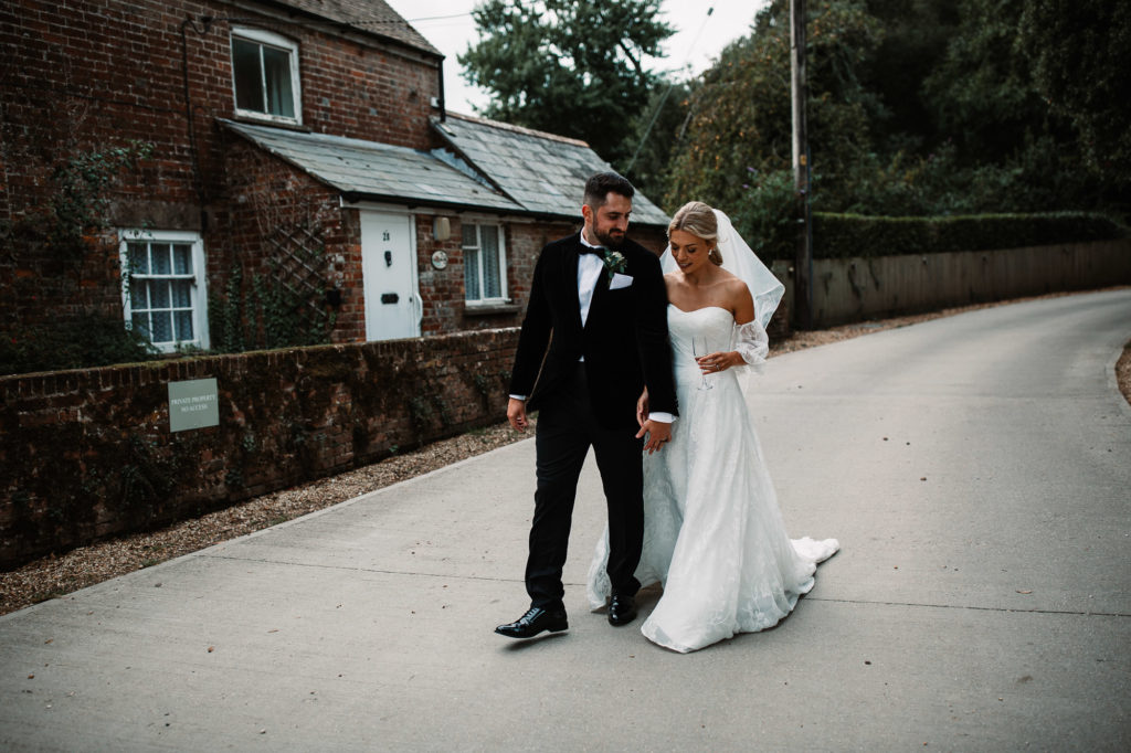 bride and groom walking hand in hand in front of sopley mill
