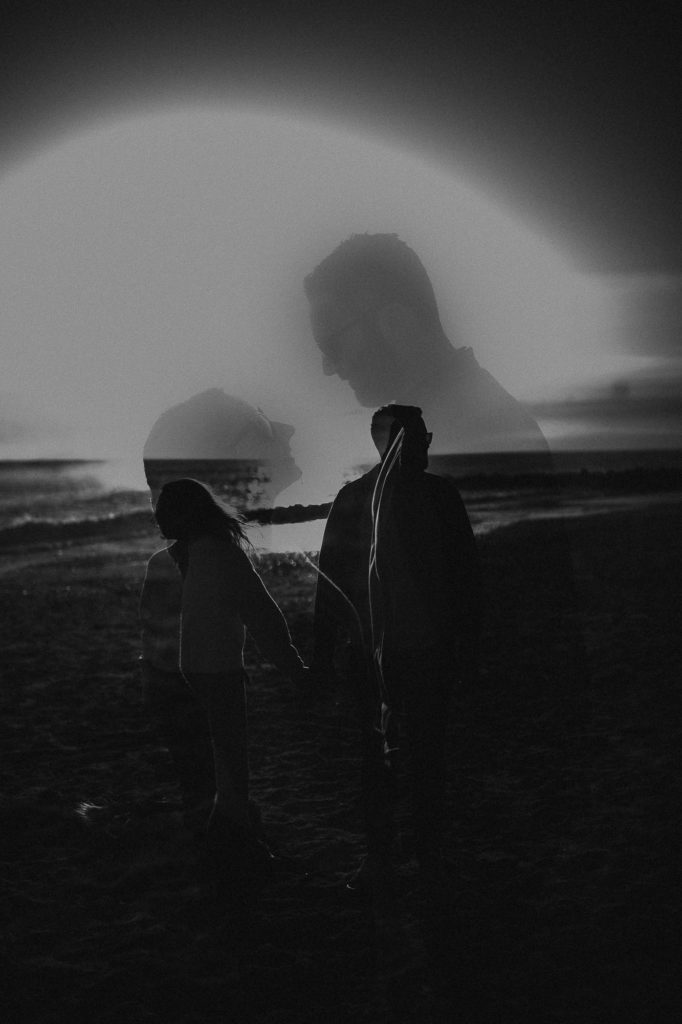 Double exposure of couple in black and white on the beach looking at eachother