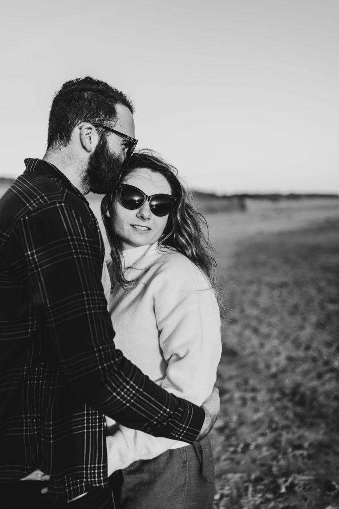 black and white shot of couple on the beach wearing sunglasses