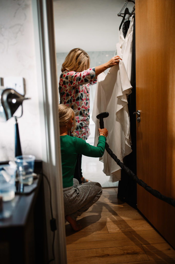 bride steaming her dress with the help of her mum