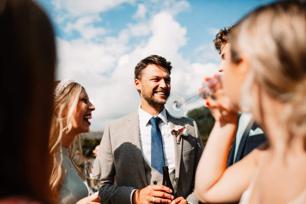 groom in the sunlight laughing with guests