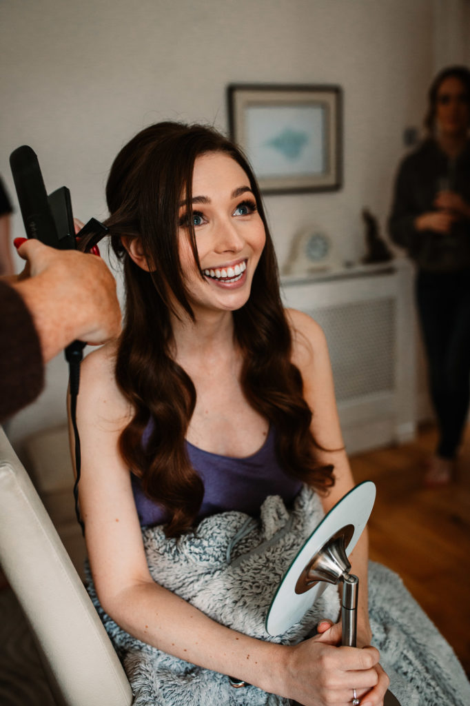 bride having her hair done and smiling