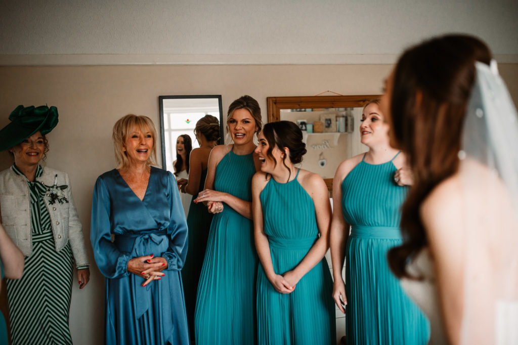 mother of the bride and bridesmaids looking at the bride fully dressed