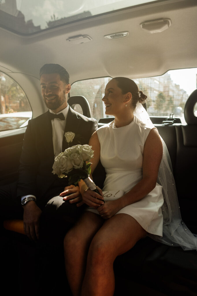 bride and groom laughing together in a taxi in London