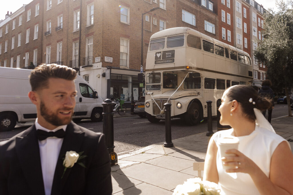 bride and groom in the sunshine looking at a bus