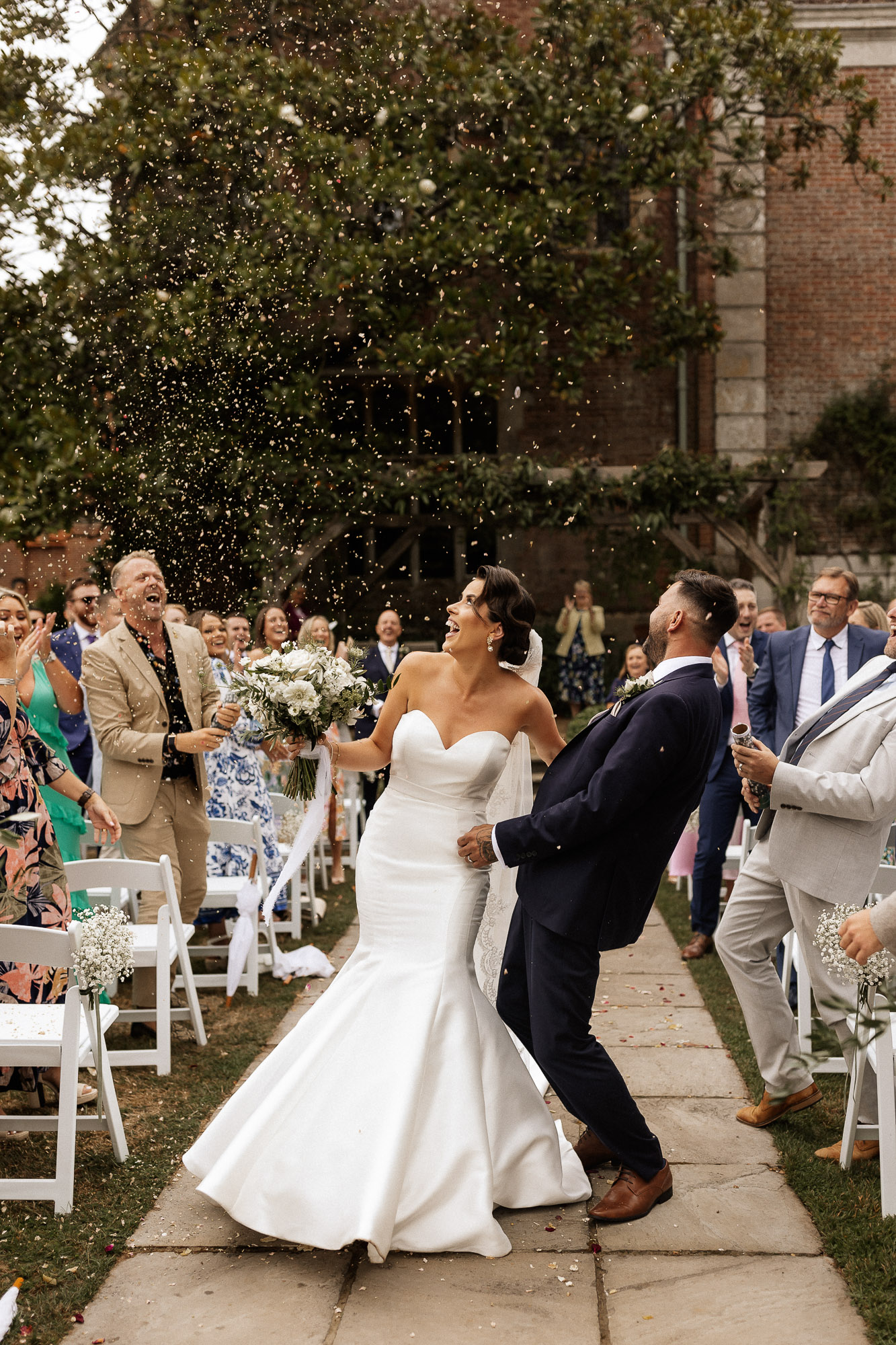 bride and groom laughing at the confetti being thrown at them