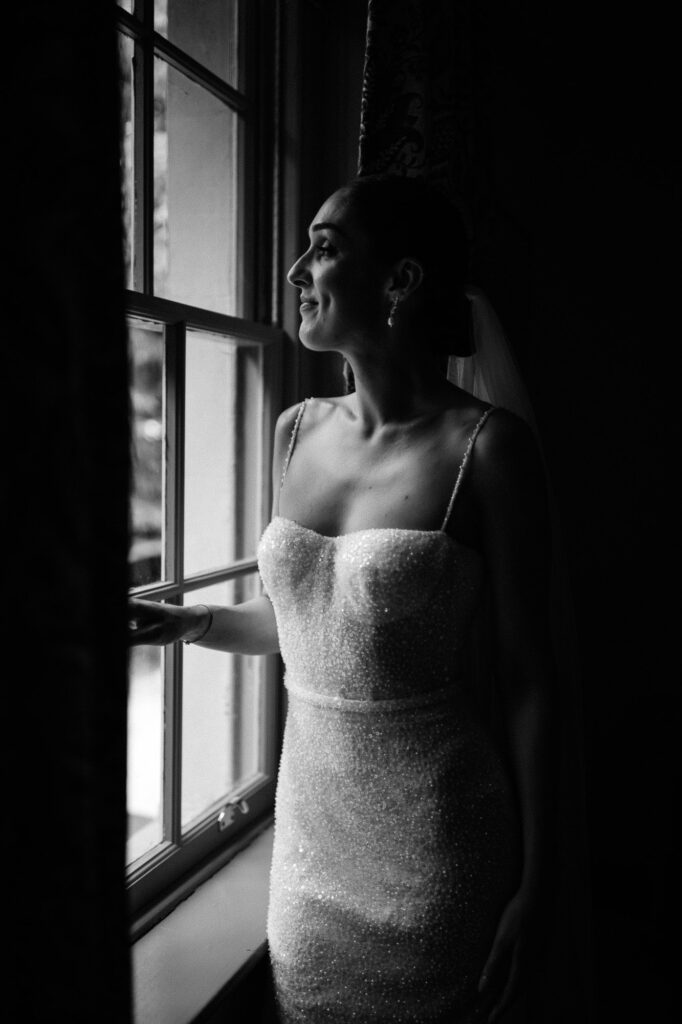black and white shot of bride looking out the window