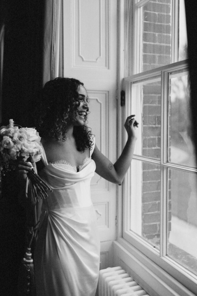 Bride looking over the window at Avington Park